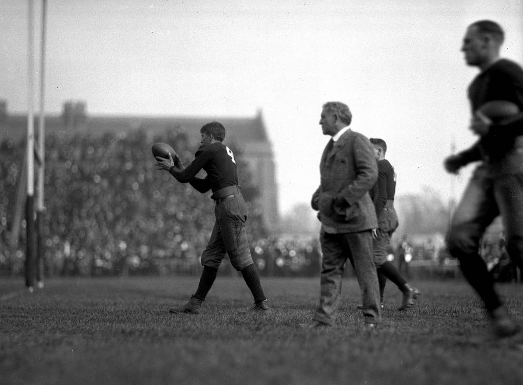 El entrenador Amos Alonzo Stagg, centro, observa a Otto Strohmeier para el equipo de fútbol de la Universidad de Chicago, alrededor de 1920. 